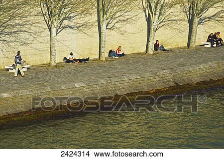 Sitting against a wall in the warm sunlight along a river; Paris, France View Large Photo Image Picture - Sitting against a wall in the warm sunlight along a river; Paris, France. Fotosearch