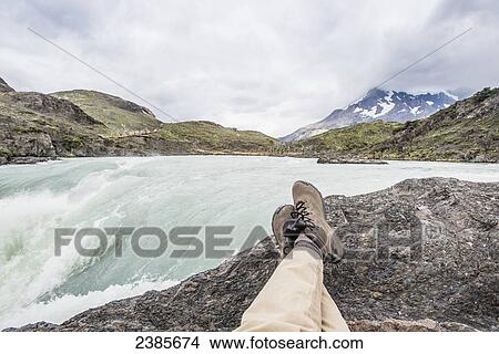 Picture - Sitting on a rock with a view of a rushing mountain river; Tores Del Paine, Magallanes, Chile. Fotosearch