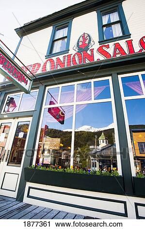 Stock Image - Skagway, Alaska, United States Of America; Reflection In The Window Of The Red Onion Saloon In Klondike Gold Rush National Historic Park. Fotosearch