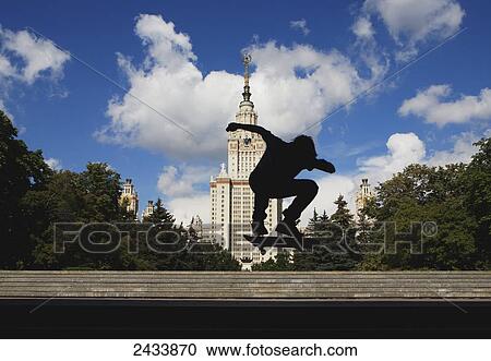 Stock Image - Skateboader getting air in front of Moscow State University's Main Building, the tallest educational building in the world; Moscow, Russia. Fotosearch