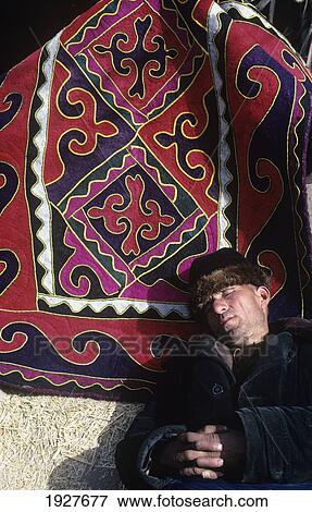 Stock Photo - Sleeping Man Trying To Sell Carpets On Kashgar Bazaar; Ancient Silk Road, Kashgar, Xinjiang, China. Fotosearch