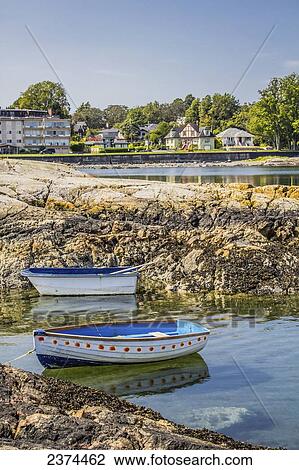 Stock Image - Small boats are tied to the rocky shore in a cove; Victoria, British Columbia, Canada. Fotosearch