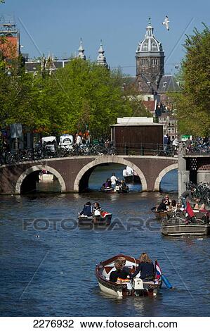 Small boats going along canal with St Nicholas church in background; Amsterdam, Holland View Large Photo Image Stock Image - Small boats going along canal with St Nicholas church in background; Amsterdam, Holland. Fotosearch