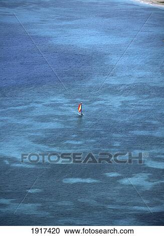 Stock Image - Small Catamaran Sailing In The Shallow Waters, Reduit Beach, Rodney Bay As Seen From The Top Of The Fort, Pigeon Island, St Lucia.. Fotosearch