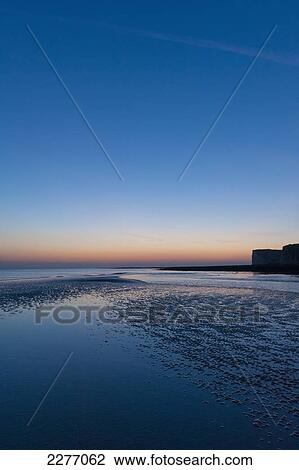 Stock Image - Small pool in sand at low tide at Cuckmere Haven at dusk; East Sussex, England. Fotosearch