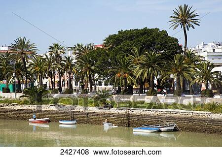 Stock Photo - Small rowboats tethered to the wall at the water's edge; El Puerto de Santa Maria, Andalucia, Spain. Fotosearch