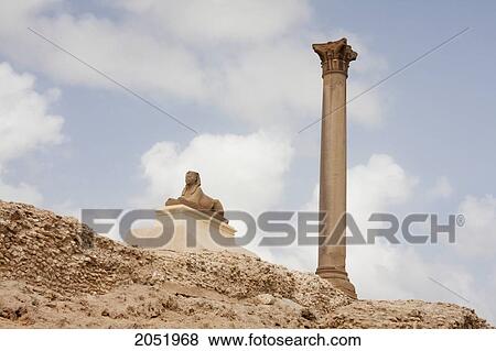 Stock Photo - Small Sphinx And Column Of Red Granite 30M Tall, Erected In 298 Ad In Honour Of The Emperor Diocletian On The Acropolis Of Alexandria. It Was Wrongly Named PompeyÃƒÆ’Ã¢â‚¬Â S Pillar By Travellers During The Middle Ages, Alexandria, Al Iskandar. Fotosearch