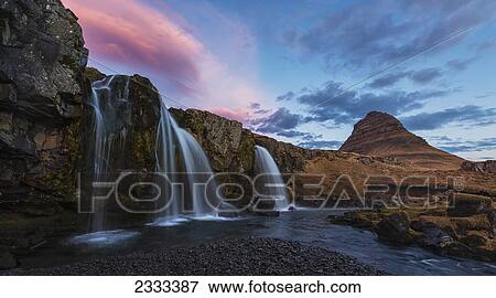 Small Waterfall With Kirkjufell In The Distance And Clouds Lit By The Rising Sun; Snaefellsnes Peninsula, Iceland View Large Photo Image Stock Photo - Small Waterfall With Kirkjufell In The Distance And Clouds Lit By The Rising Sun; Snaefellsnes Peninsula, Iceland. Fotosearch
