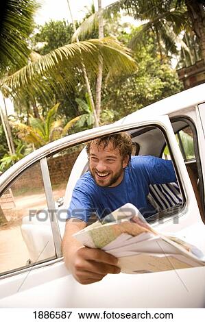 Stock Photo - Smiling Backpacker In Back Seat Of Taxi Holding Map. Fotosearch