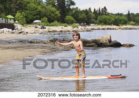 Stock Photograph - Smiling Boy Standing On A Surfboard, Lake Winnipeg, Gimli, Manitoba, Canada. Fotosearch