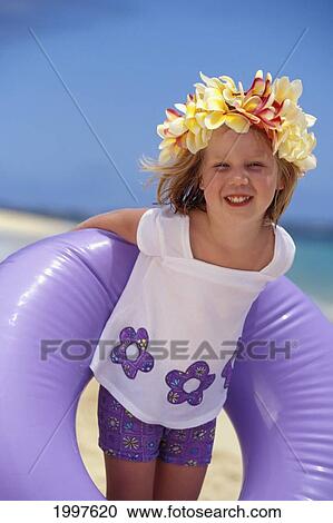 Stock Image - Smiling Girl With Plumeria Haku Holds Purple Inner Tube Behind Back. Fotosearch