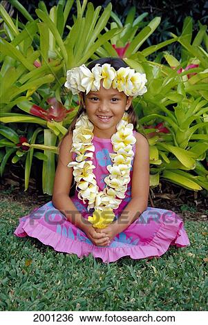 Stock Photograph - Smiling Local Girl Sits Cross-Legged With Plumeria Haku And Lei, Grass Greenery Background D1439. Fotosearch