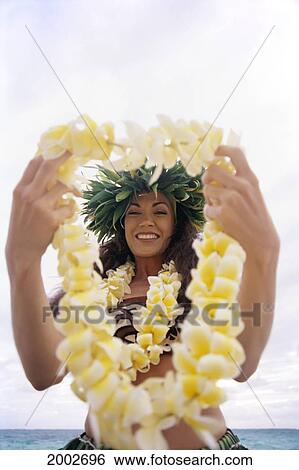 Stock Photograph - Smiling Local Woman Holds Plumeria Lei Out In Front, About To Pass To Someone. Fotosearch