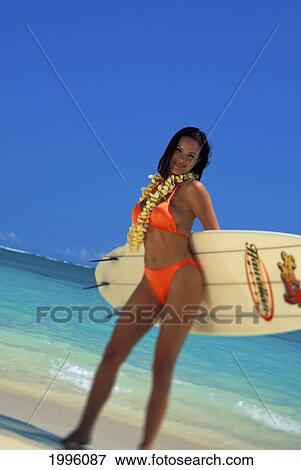 Stock Photo - Smiling Woman In Pink Bikini Stands On Beach Holding Surfboard Behind Back. Fotosearch