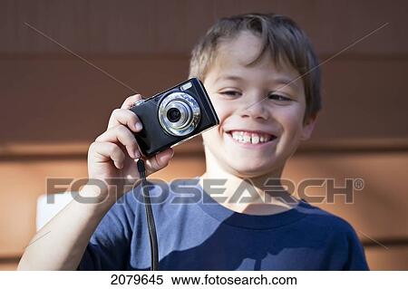 Stock Photography - Smiling Young Boy Taking A Photograph. Gimli, Manitoba, Canada.. Fotosearch