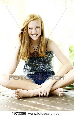 Smiling Young Woman Sits With Her Legs Crossed On A Wooden Floor. View Large Photo Image Stock Photograph - Smiling Young Woman Sits With Her Legs Crossed On A Wooden Floor.. Fotosearch