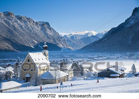 Stock Image - Snow Covered Alpine Scenery With Mountains, Picturesque Church, Ski And Snowboard Resort At Waidring, Austrian Alps, Austria. Fotosearch