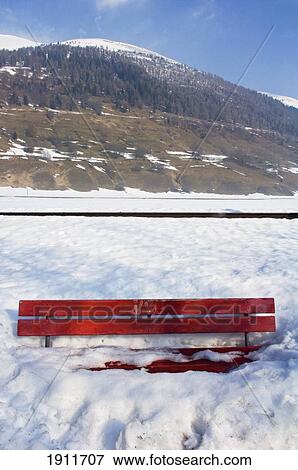 Stock Photo - Snow-Covered Bench In Front Of Mountain, Goms Valley, Switzerland. Fotosearch