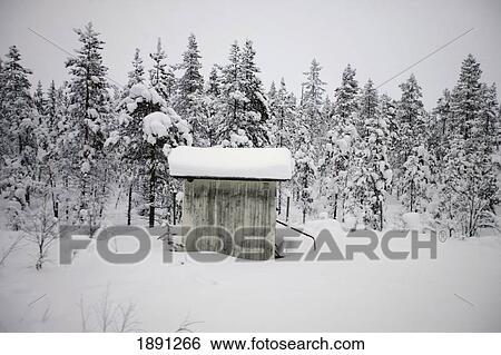 Stock Photograph - Snow Covered Cabin By Forest. Fotosearch