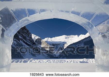 Stock Image - Snow Covered Mountain And Frozen Lake Framed In A Ice Castle Window; Lake Louise, Alberta, Canada. Fotosearch