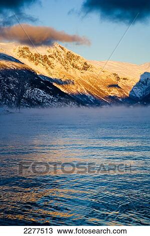 Snow covered mountains illuminated by golden sunlight at sunset; Ortnevik, Sognefjord, Norway View Large Photo Image Stock Image - Snow covered mountains illuminated by golden sunlight at sunset; Ortnevik, Sognefjord, Norway. Fotosearch