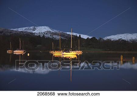 Snow On The Tops Of The Mountains Reflected In The Water With Boats Moored In Lake Windermere; Cumbria England View Large Photo Image Stock Photo - Snow On The Tops Of The Mountains Reflected In The Water With Boats Moored In Lake Windermere; Cumbria England. Fotosearch