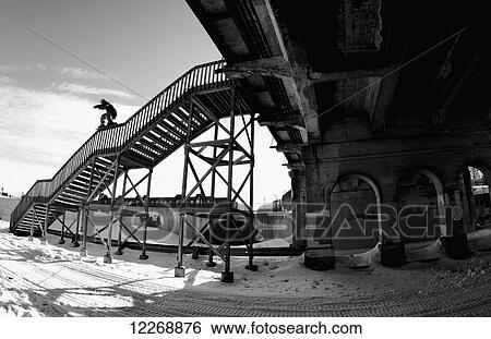 Stock Photograph - Snowboarder balancing on the handrail of steps; Minnesota, United States of America. Fotosearch