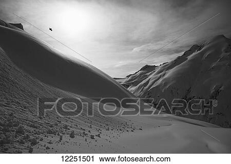 Stock Image - Snowboarder doing a trick mid-air; Haines, Alaska, United States of America. Fotosearch