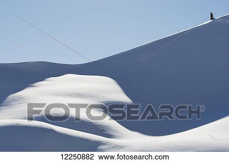 Stock Image - Snowboarder on a snowy slope against a blue sky; Austria. Fotosearch