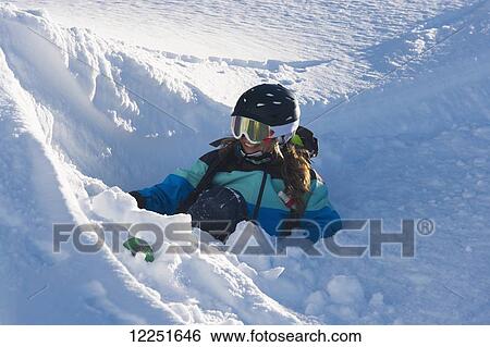 Stock Photograph - Snowboarder sitting in deep snow; St. Moritz, Graubunden, Switzerland. Fotosearch