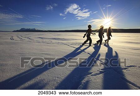 Stock Image - Snowshoers In Bright Winter Sun On The Frozen Teslin Lake, Yukon. Fotosearch