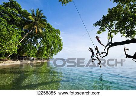 Stock Photography - Solomon Island kids swinging from a rope; Gizo, Western Province, Solomon Islands. Fotosearch