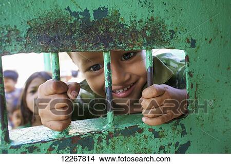Son of jail worker peaks out from behind bars; Phnom Penh, Cambodia View Large Photo Image Picture - Son of jail worker peaks out from behind bars; Phnom Penh, Cambodia. Fotosearch