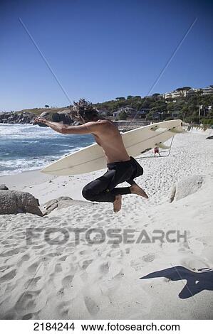Picture - South Africa, Camp's Bay; Cape Town, Man Going Surfing. Fotosearch