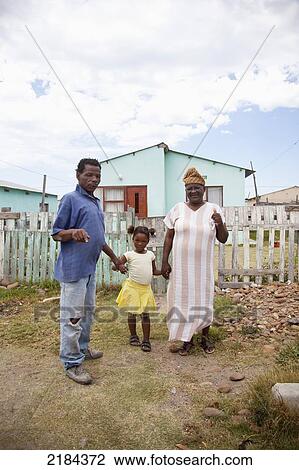Stock Image - South Africa, Garden Route, Port Elizabeth, Portrait Of Family By Fence; New Brighton. Fotosearch