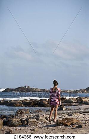 Stock Photograph - South Africa, Young Woman Walking Along Seashore; Mossel Bay. Fotosearch