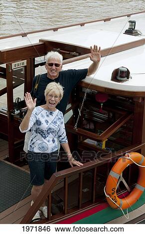 Stock Photograph - South East Asia, Singapore, Senior Tourist Couple On Boat Traveling On River.. Fotosearch