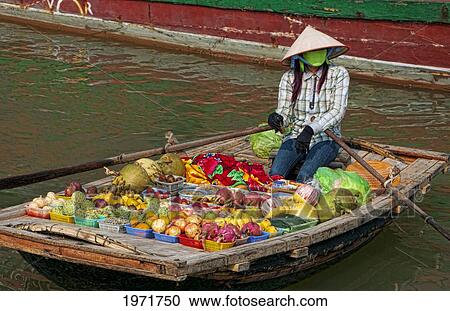 Stock Image - South East Asia, Vietnam, Ha Long Bay, Vietnamese Woman Sells Fresh Fruit From Her Small Boat.. Fotosearch
