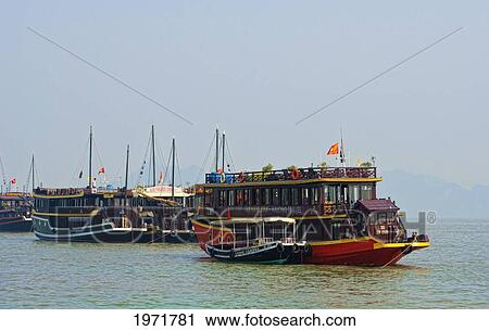 Stock Image - South East Asia, Vietnam, Ha Long Bay, Traditional Old Boats Arrive In Bay With Tourists.. Fotosearch