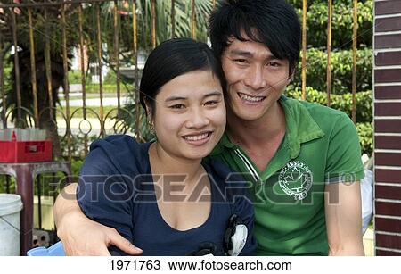 Stock Image - South East Asia, Vietnam, Hanoi, Student Couple Relaxes On College Campus For Their Portrait.. Fotosearch