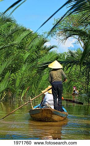Stock Image - South East Asia, Vietnam, Saigon, Mekong Delta River, Women Paddle Down A Muddy River.. Fotosearch