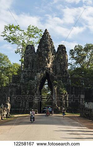 Stock Photo - South gate of Angkor, connecting Bayon Wat and Angkor Wat, in the laterals many buddhas are holding a big snake, the gate is made by a tower with four buddha faces; Siem Reap, Cambodia. Fotosearch