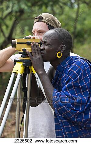 Stock Image - South Western Ethiopia, Omo Valley, Southern Mursiland, Local Mursi warrior with archaeologist; Dirikoro. Fotosearch