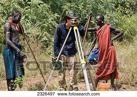 Stock Photo - South Western Ethiopia, Omo Valley, Southern Mursiland, Two local Mursi warriors with archaeologist; Dirikoro. Fotosearch