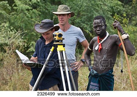 South Western Ethiopia, Omo Valley, Southern Mursiland, Local Mursi warrior with archaeologists; Dirikoro View Large Photo Image Stock Photo - South Western Ethiopia, Omo Valley, Southern Mursiland, Local Mursi warrior with archaeologists; Dirikoro. Fotosearch