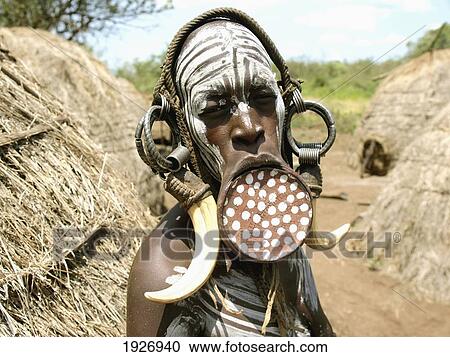 Stock Image - Southern Ethiopa, Mursi Woman with Warthog Tusks Decoration; Omo Valley. Fotosearch