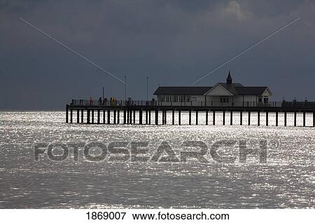 Stock Photo - Southwold, Suffolk, England; Fishermen Standing On A Pier And A Building Along The Coast Of The North Sea. Fotosearch