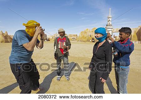 Stock Image - Souvenir Sellers Descend On Tourists Visiting The Old Star Wars Set Mos Espa; Chot El Jerrid, Tunisia, North Africa. Fotosearch