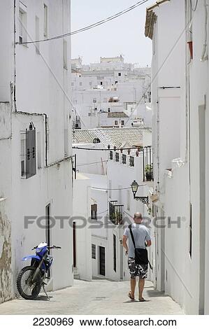 Spain, Andalucia, Costa De La Luz, Man Walking Past Motorbike; Vejer De La Frontera View Large Photo Image Stock Photo - Spain, Andalucia, Costa De La Luz, Man Walking Past Motorbike; Vejer De La Frontera. Fotosearch