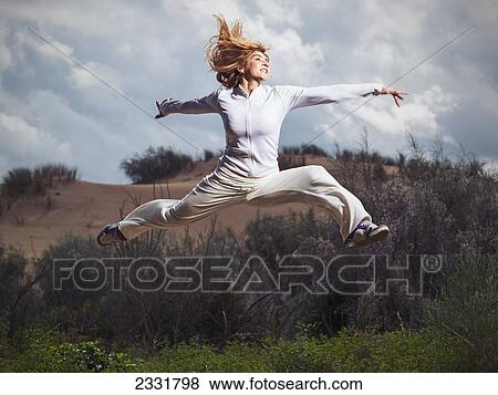 Stock Photo - Spain, Andalusia, Cadiz, Costa De La Luz, Mature Woman Making Large Leap At Sand Dune; Tarifa. Fotosearch